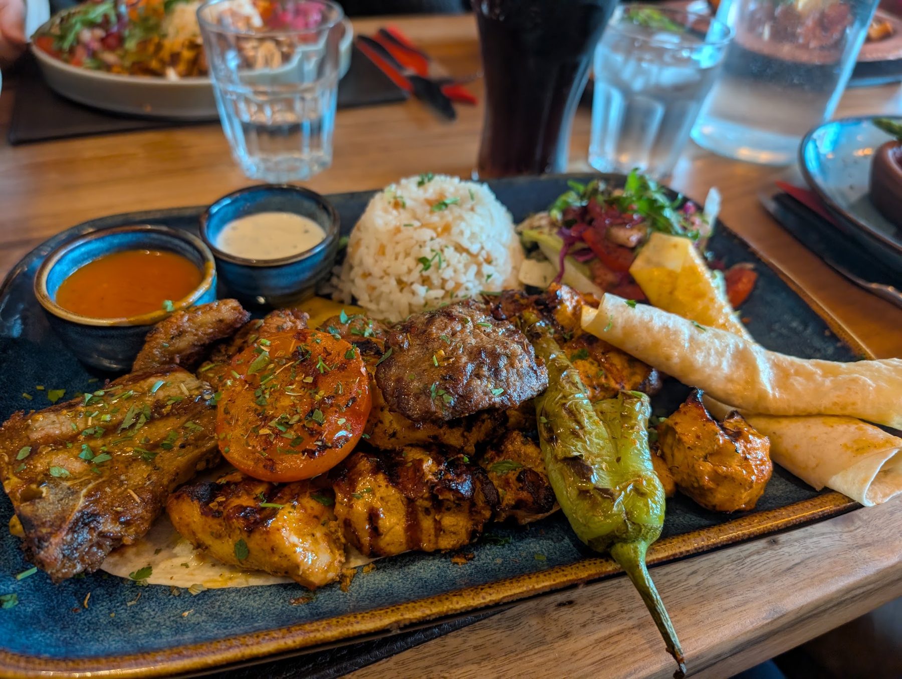 Mixed grill platter with rice, grilled pepper and dips